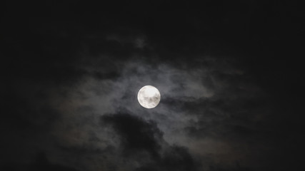 Naklejka na ściany i meble Dark black clouds covering full moon in the sky, frightful scenery