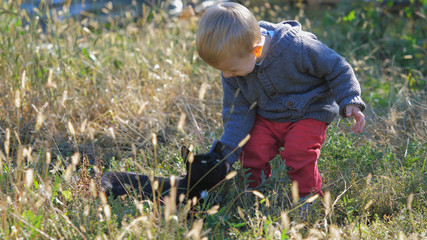 Cute blonde hair baby child caressing black cat in nature