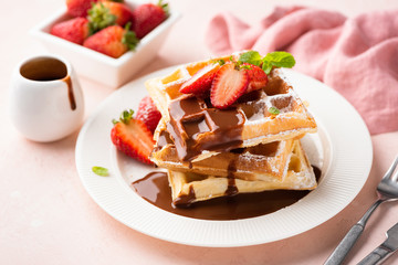 Belgian waffles with strawberry and chocolate sauce on white plate. Tasty breakfast, sweet dessert food