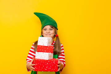Child dressed as Santas helper holding Christmas presents