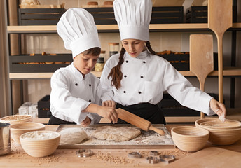 Little bakers preparing dough on table
