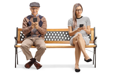 Senior man and a young lady sitting on a bench with smartphones