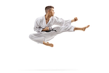 Young man in karate kimono jumping and kicking