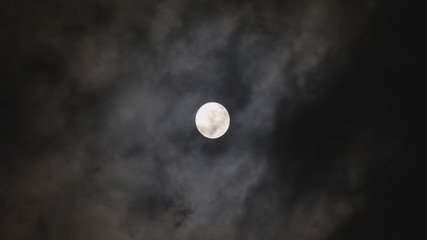 Naklejka na ściany i meble Black clouds cover and real white moon, the good behind evil