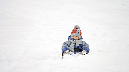 Fototapeta na wymiar Baby child sitting on snow, isolated boy in white nature