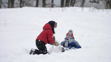 Fototapeta na wymiar Little kid and big brother play in the snow