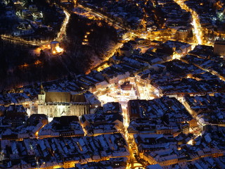 Aerial top view night panorama of snowed roofs and Christmas tree in city center