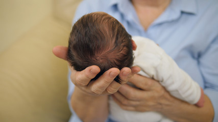 Newborn baby child head on parent arms, holding most precious life treasure