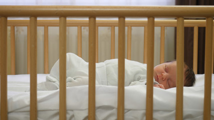 Fototapeta na wymiar Newborn child sleeping in a baby crib, peaceful dreams