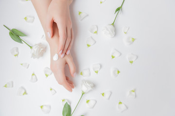 Close-up beautiful sophisticated female hands with flowers on white background. Concept care, anti-wrinkles, anti-aging cream, spa