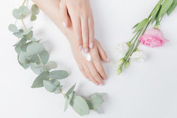 Close-up beautiful sophisticated female hands with pink flowers on white background. Concept care, anti-wrinkles, anti-aging cream, spa