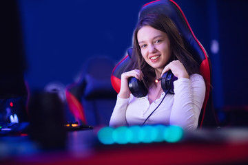 Streamer beautiful girl professional gamer smile playing online games computer with headphones, neon color © Parilov
