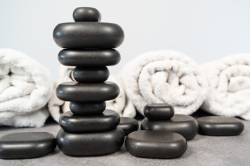 stack of black basalt stones for massage on a white background in front of clean towels balance spa treatment concept