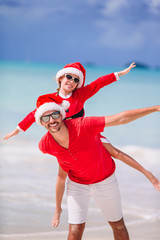 Fototapeta premium Father and daughter in Santa Hat have fun at tropical beach