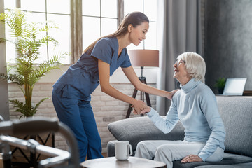 Happy female professional caregiver taking care of elderly woman at home - Powered by Adobe