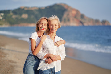 Outdoor portrait of smiling happy caucasian senior mother with her adult daughter hugging and...