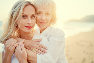 Outdoor close up portrait of smiling happy caucasian senior mother with her adult daughter hugging...
