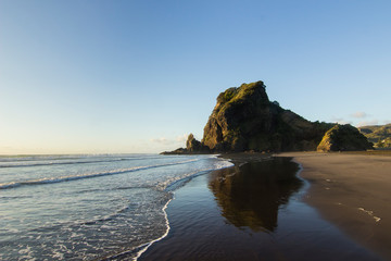 Lion rock on Piha beach New Zealand, reflection in the ocean 
