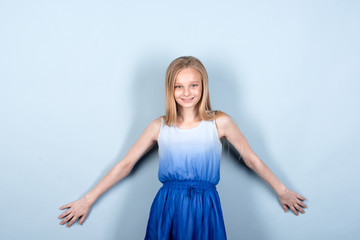 Naklejka premium Little blonde girl in summer dress trying to be a fashion model. First steps in the profession. Professional skills, early education. Photo shot in the studio. Isolated on gray, Copy space.