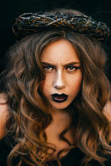 Effective stylish incredible female model in black witch halloween costume prepearing for party over black isolated background