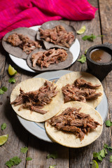 Mexican slow cooked lamb tacos also called barbacoa on wooden background