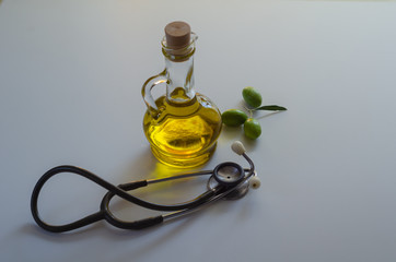 Olive oil, olives and stethoscope on white background.