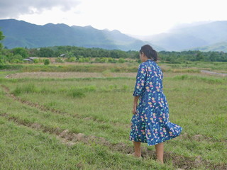 Asian woman enjoys walking in a field in a rural area - getting outside and engage with nature provides positive impact on health and development