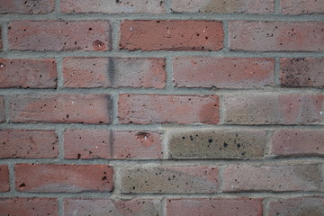 Head-on view of a modern, red brick wall with worn damage.