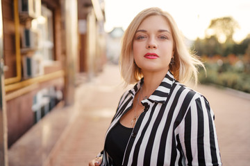 Fototapeta premium Outdoor portrait of happy young woman walking by city street.