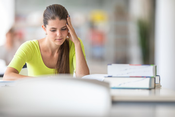 Cute female university/highschool student with books in library