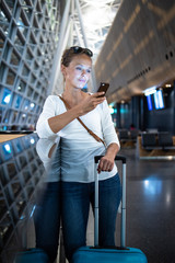 Young woman with her luggage at an international airport, waiting for her flight in the lounge zone after going through the  security check procedure