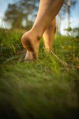 Barefoot young woman in green meadow; Harmony with nature - concept of vacation, summer leisure, naturism, relax