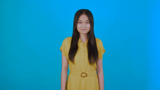 attractive asian woman smiling isolated on blue background 4K