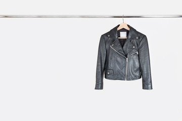 Fashion leather jacket hanging on hanger on white background