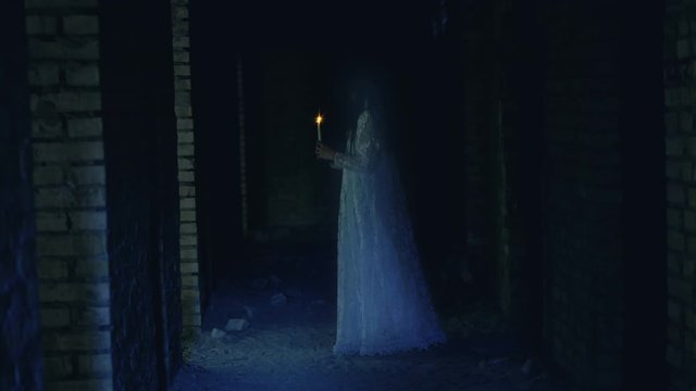 Ghost of dead woman wandering old house with burning candle, horror thriller