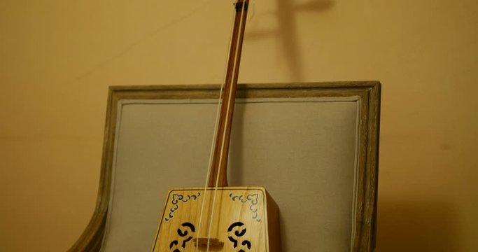 Close shot of bearded Musician playing erhu, chinese traditional two stringed instrument. handsome caucasian mal musician wearing white shirt and pants
