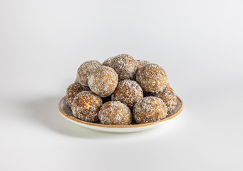 Homemade energy balls with dried apricots, raisins, dates, walnuts, almonds and coconut. Healthy sweet food. Energy balls in a plate on a white background