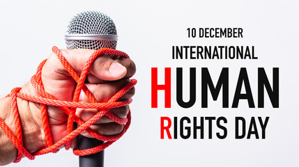Hand holding microphone and have roped on fist hand with 10 december international HUMAN RIGHTS DAY text