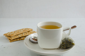 Mug with a bag of green tea. Against the background of cookies with sunflower seeds.