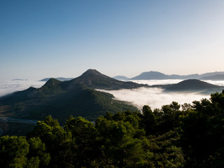 Plakat panorama of mountains with low mists at dawn
