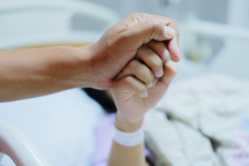 Close up focus on the Shake hands of a patient sick encourage encouragement on the bed in hospital ward.