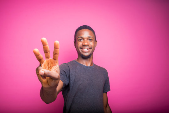 African Man Over Pink Wall Happy And Counting Three With Fingers