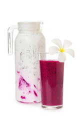 Closeup composition of glass with red dragon fruit juice and a jug of milk shake with coconut milk decorated with flower isolated at white background.  vegan food, detox and healthy lifestyle.