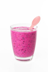 Closeup glass of berries milk shake with plastic spoon isolated at white background. Concept of healthy vegan lifestyle and super food