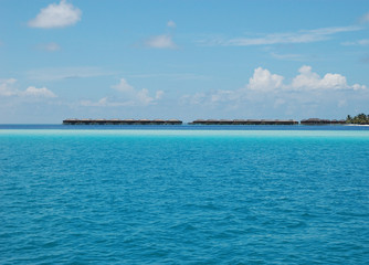 A far-away line of the luxury ocean cottages of the Vilamendhoo Island in the Maldives