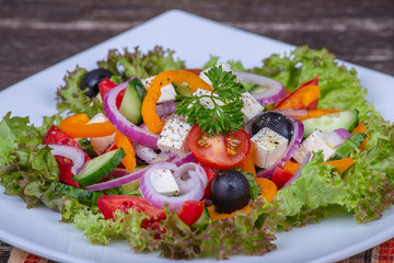 Greek salad of fresh cucumber, tomato, sweet pepper, lettuce, red onion, feta cheese and olives with olive oil. Healthy food