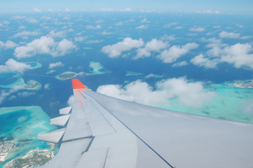 A plane amidst the clouds and coral islands of the Maldives