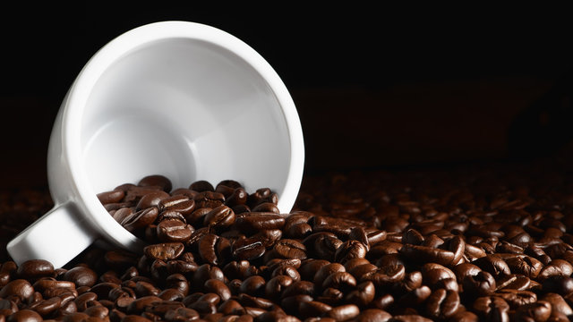 food and beverage background of roasted coffee beans in coffee cup and scattered around