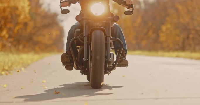 Motorcycle wheels close-up. Autumn road, leaves are flying.