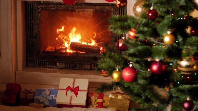 4k footage of lots of Chrismtas gifts and presents under Christmas tree next to burning fireplace in living room